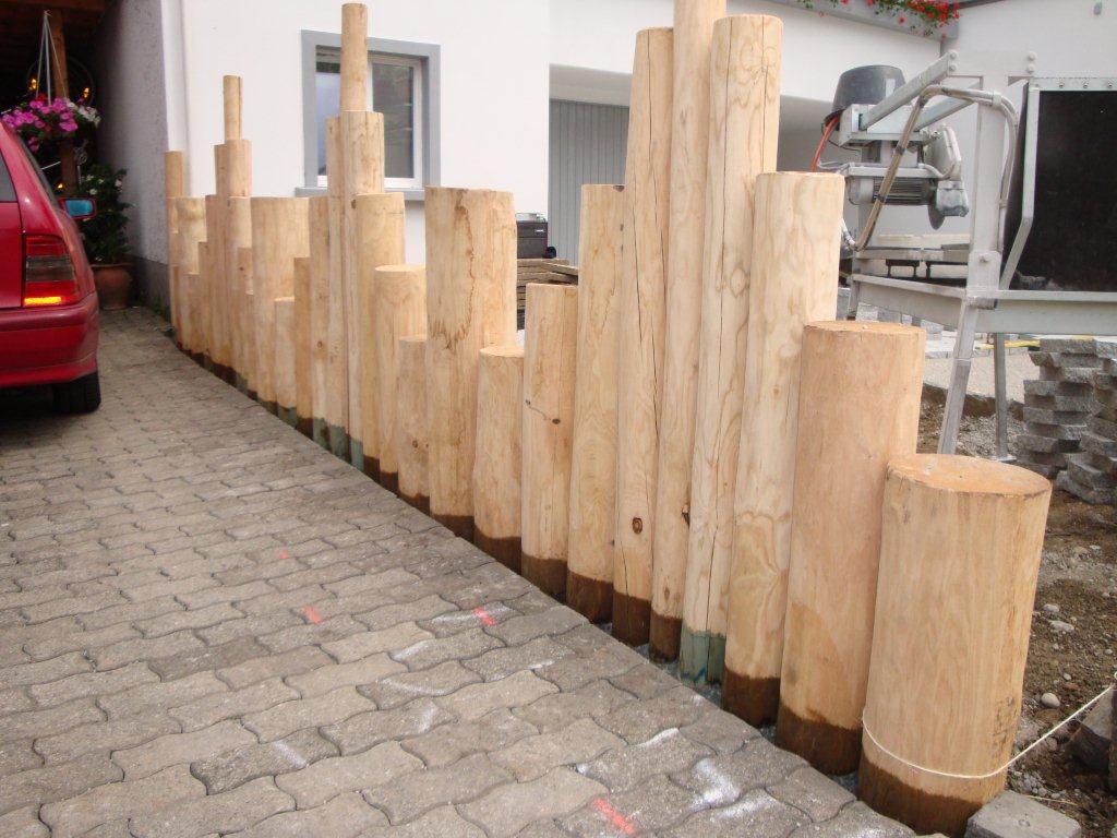 Palisaden Zaun aus Kastanien Rundholz Pfählen. Stammholz mit Stufen als Mauer.